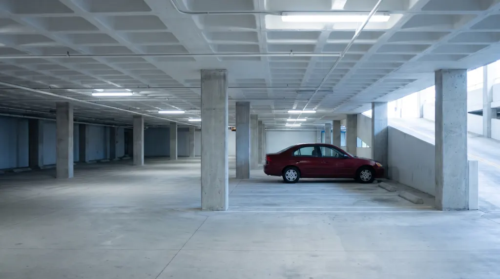 A condominium parking garage with concrete columns and a ramp.